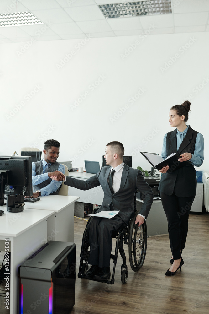 Wall mural successful businessman in wheelchair greeting his african male colleague in the morning