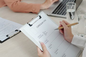 Close-up image of applicant writing down her personal information and skills before job interview