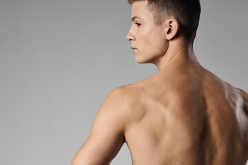 Fototapeta premium strong athlete with bulging arm muscles naked back back view gray background
