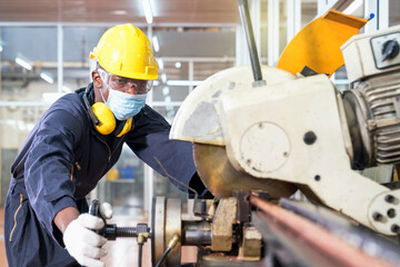 A factory mechanic is using a chainsaw to cut copper pipes. An expert technician is inspecting industrial machinery in a steel manufactory.