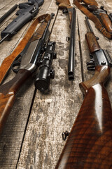 Many hunting rifles on weathered wooden surface