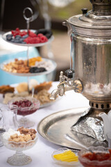 View of a round table with tea-ware from a traditional Russian samovar. Bakery, sweet food concept. Delicious pastries, jam and berries on the table. Birthday celebration. Children's holiday.