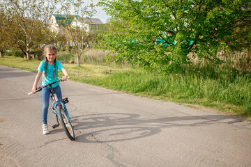 Fototapeta premium Little girl learning to ride a bicycle, happy summer in village, healthy lifestyle, childhood, sport and recreation, eco-friendly transport and responsible lifestyle