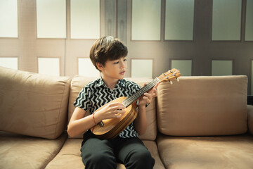 a little boy sitting on sofa and playing guitar