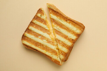 Tasty grilled sandwich on beige background, close up