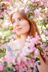 Portrait of a red-haired spring girl. Beautiful young woman in pink flowers enjoying the apple orchard. Allergy free concept.