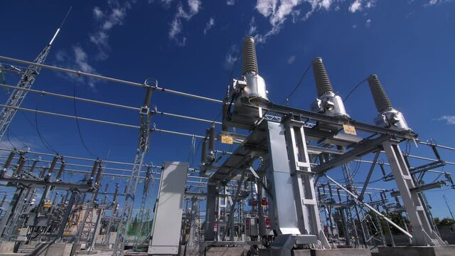Supports with insulators and transformers at modern electrical distribution substation against blue sky close view