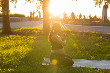 Young pregnant woman meditating in nature, practice yoga. Care of health and pregnancy