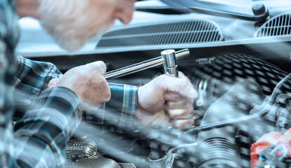 Car mechanic working on car engine; light effect