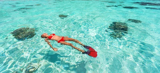 Foto op Plexiglas Snorkel woman swimming in the turquoise ocean sea relaxing floating on luxury travel vacation above underwater coral reefs. Water sport diving active lifestyle banner. © Maridav