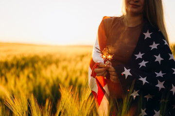 Happy young woman holding American flag at sunset. 4th of July. Independence Day.