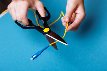 Destroy optical fiber with scissors. Isolated on blue