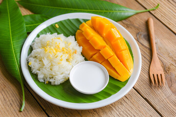 Ripe mango rice cooked with coconut milk, Sticky rice summer tropical fruit food Asian Thai dessert sweet mango peel and sliced on plate and fresh leaves - 436607800