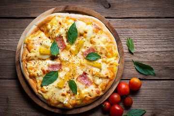 Tasty pizza homemade italian food style, pizza cheese ham and pineapple fruit cooking ingredients tomatoes basil on wooden background, Top view of pizza cheese italian food style. Flat lay