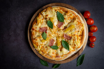 Tasty pizza homemade italian food style, pizza cheese ham and pineapple fruit cooking ingredients tomatoes basil on black background, Top view of pizza cheese italian food style. Flat lay