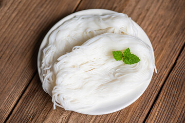 Thai rice noodles vermicelli on plate and wooden background, noodles for curry Thai food