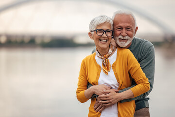 Mature husband and wife, smiling for the camera, by the river