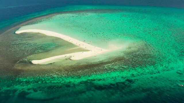 Tropical white island and sandy beach with tourists surrounded by coral reef and blue sea, aerial view. Sandbar Atoll. Island with sand bar and coral reef. Summer and travel vacation concept, Camiguin