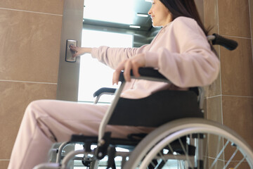 Fototapeta na wymiar Smiling woman in wheelchair presses button of elevator