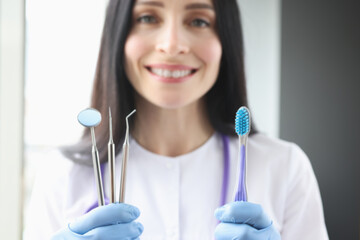 Smiling female dentist holding tool and toothbrush in her hands