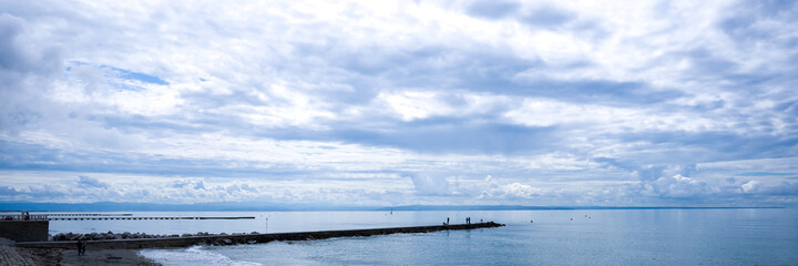 Fototapeta na wymiar pier with fishermen, in the background the sea and a cloudy sky. banner