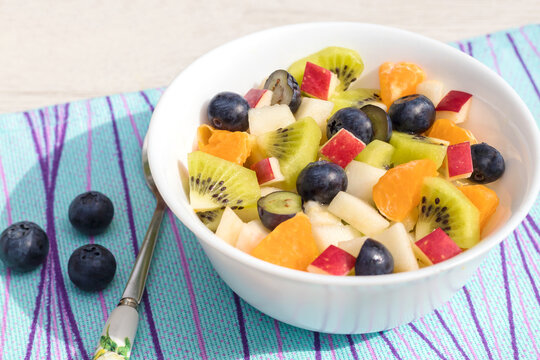 Fresh fruit vitamin-rich delicious salad in a white clay bowl. 