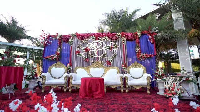 Indian wedding hall with flower decoration & Royal Chairs on the stage. Outdoor wedding stage setup for ceremony. 