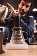Fototapeta na wymiar Pressurized coffee brewing using an aeropress - the barista presses the piston