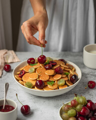 cereal pancackes with cherries and yogurt, berries, breakfast with woman hand