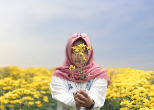 Midsection Of Person Holding Yellow Flower In Field