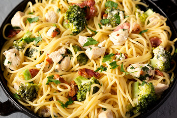 Homemade Chicken Bacon Broccoli Alfredo in a cast-iron pan on a gray background, side view. Close-up.