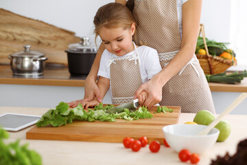 Obraz na płótnie Canvas Happy woman and her daughter making healthy vegan salad and snacks for family feasting. Christmas, New year, Thanksgiving, Anniversary, Mothers Day. Healthy meal cooking concept