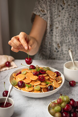 cereal pancackes with cherries and yogurt, berries, breakfast with woman hand