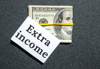 Dollars cash money and paper note with text written EXTRA INCOME. Concept of financial planning....