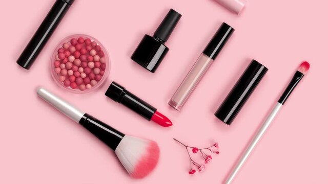 Cosmetic accessories for makeup and manicure. Skin care products on pink background with red flowers.