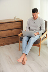 Man with laptop sitting in armchair at home. Floor heating system