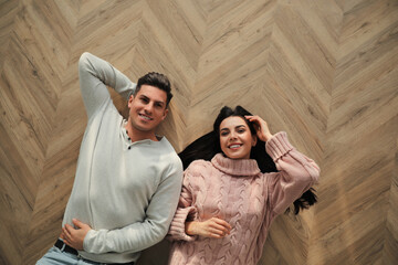 Happy couple lying on warm floor at home, top view. Heating system