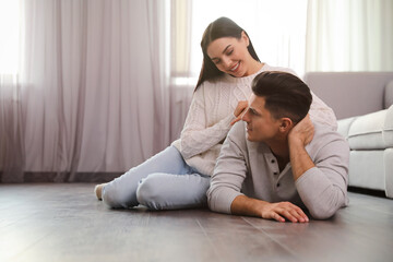 Happy couple on warm floor at home, space for text. Heating system