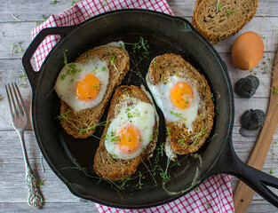 Egg in a hole served in a cast iron pan on rustic table