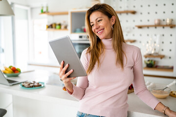 Smiling young woman with tablet in the kitchen