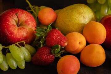 Naklejka na ściany i meble Fruit assortment of fresh fruits - grapes, strawberries, apricots, pear, apple - on black background
