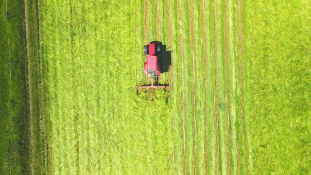 Traktor f&auml;hrt mit landwirtschaftlichem Ger&auml;t &uuml;ber frisch gemehtes Feld