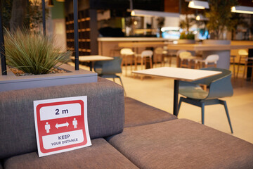 Close up background image of empty food court interior at shopping mall with red social distancing sign, copy space