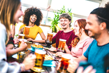 Young people toasting beer at brewery bar rooftop - Friendship life style concept with young milenial people enjoying happy hour time together at penthouse terrace pub