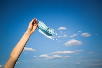  Coronavirus is finish. The end of quarantine and Corona Virus pandemic. Woman taking off and throw away medical protective mask. Enjoying life and fresh air after coronavirus pandemic.