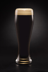 Mug with fresh stout beer with cap of foam on a black.