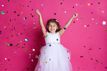 Adorable little girl and falling confetti on pink background
