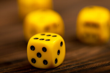 Yellow dice scattered on a wooden table. Close-up, selective focus.