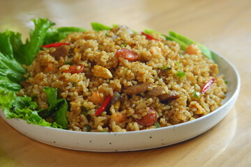 a plate of fried rice served with salad on a wooden table