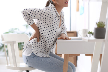 Woman suffering from back pain in office, closeup. Bad posture problem - obrazy, fototapety, plakaty